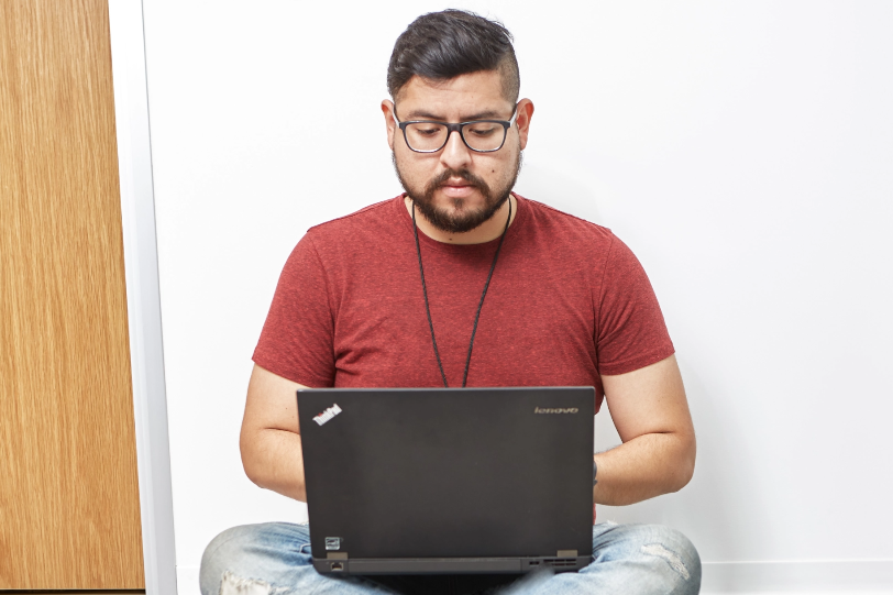 Someone sitting on the floor looking down at their computer while working