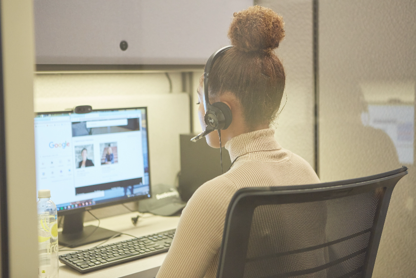 Photo of a female with a headset looking at a screen 